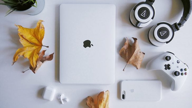 Photo of multiple devices, airpods, iphone, macbook, game controller, and external headphones