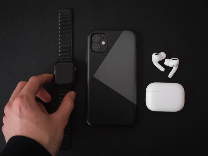 Photo of a person putting a watch beside iphone and airpods