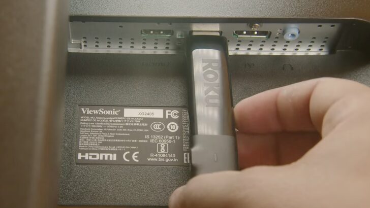Photo of person plugging roku stick on smart tv