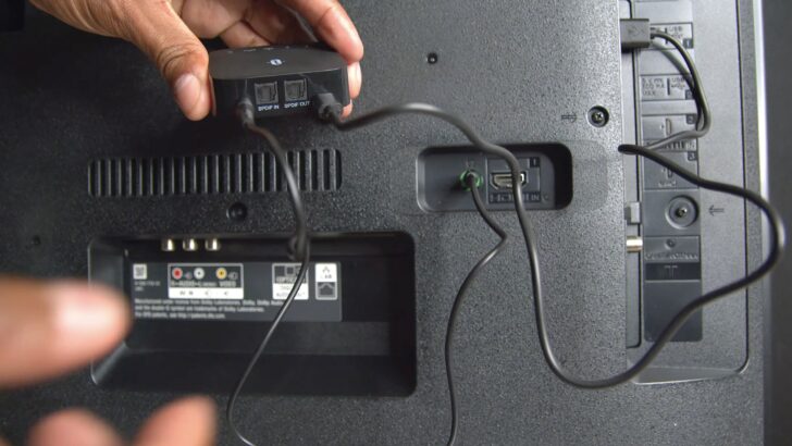 Photo of person plugging bluetooth transmitter to smart tv