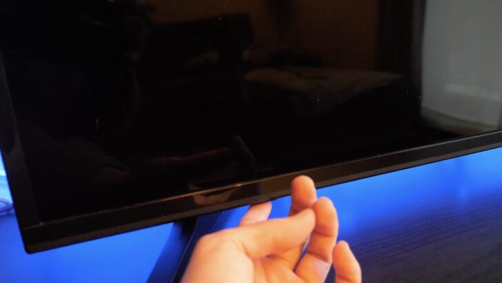 Photo of person pressing lg tv power button for a soft reset