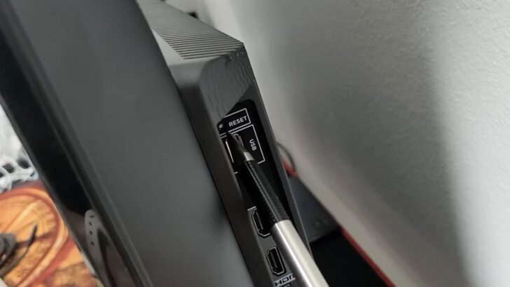 Photo of person using pen to reset tcl tv