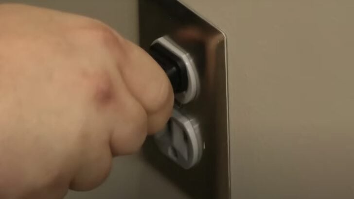 Photo of person unplugging tcl tv from the power outlet