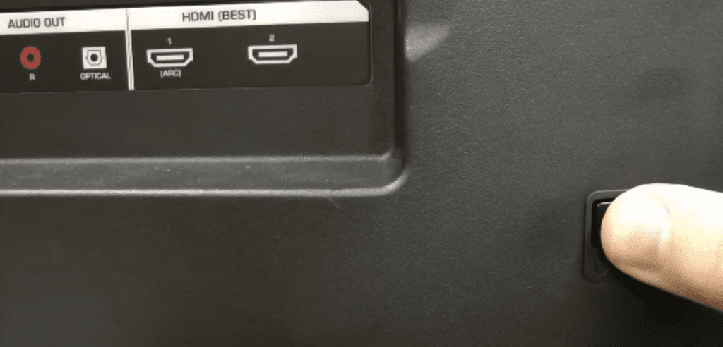 Photo of a person pressing a TV's power button to power cycle it