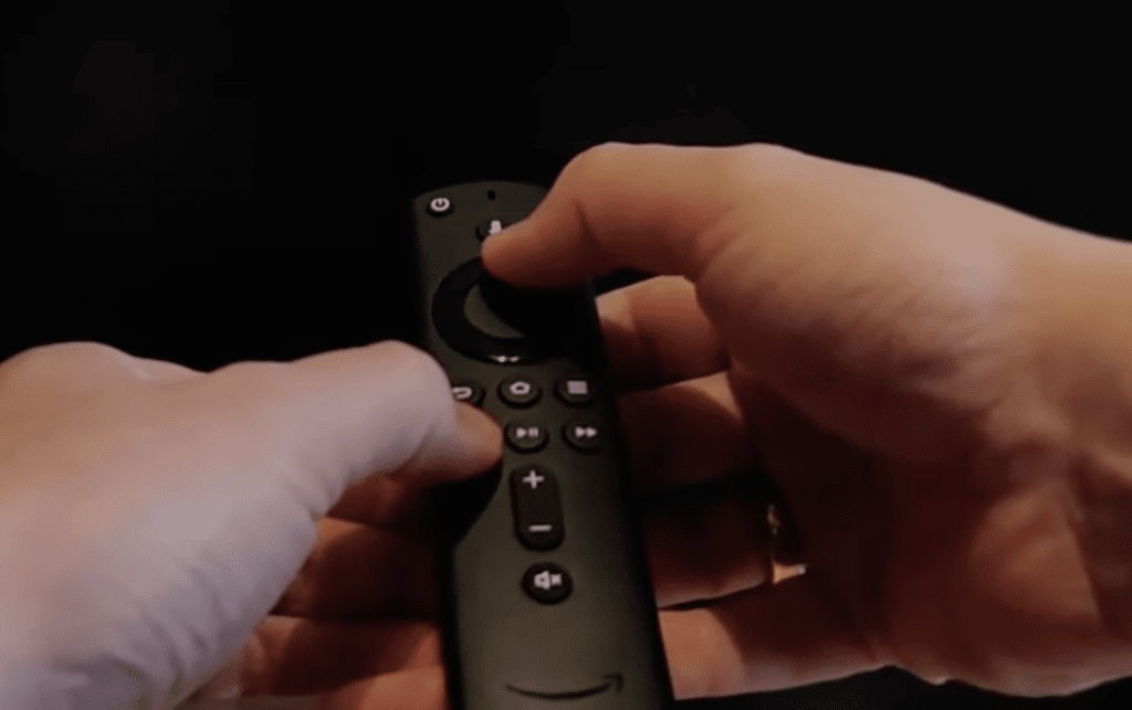 Photo of a person pressing the Up and Rewind button on a Firestick remote to change the resolution
