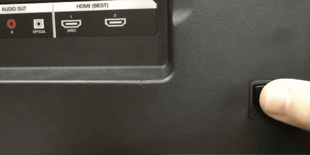 Photo of a person pressing the Vizio TV power button to drain residual electrical charge.
