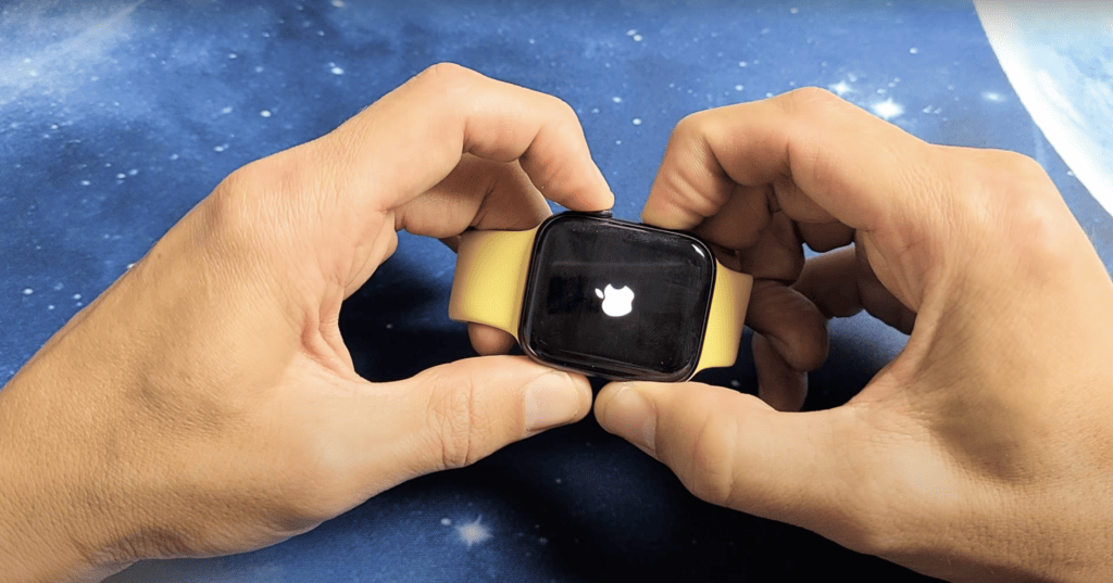 Man pressing two buttons on the side of his Apple watch until the Apple logo appears