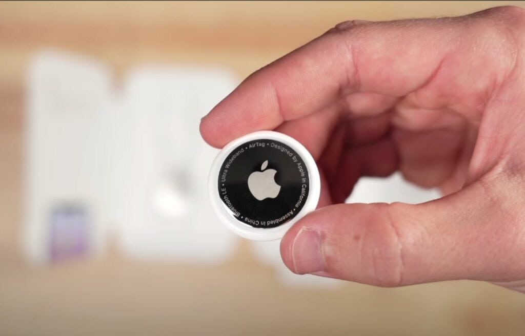 a hand holding an Apple AirTag