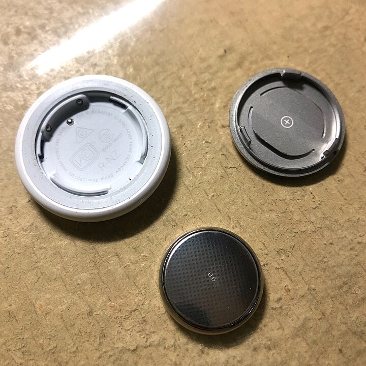 Parts of an AirTag laying on the floor