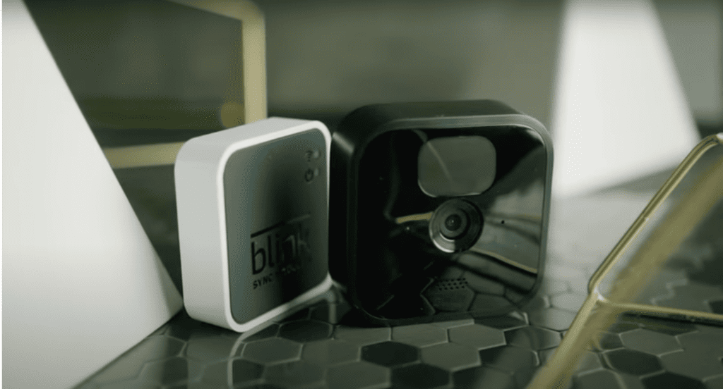 Two blink cameras laying on a glass table
