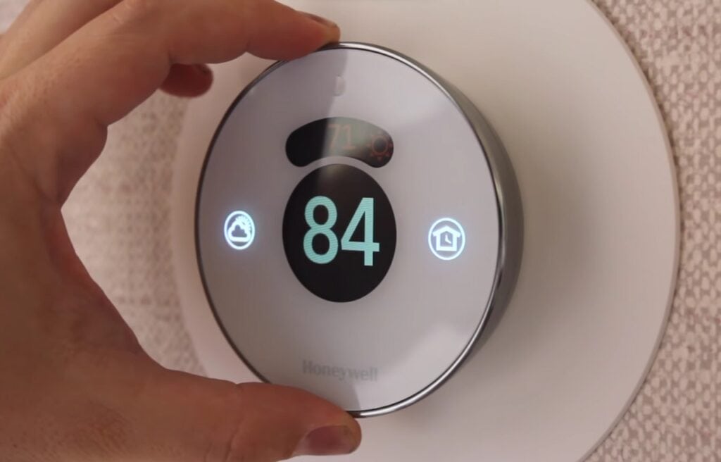 A man using the Honeywell lyric round  thermostat