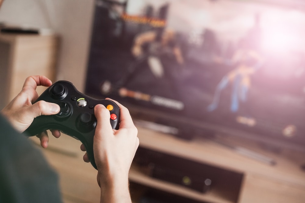 man playing games on a TV using a wireless gamepad