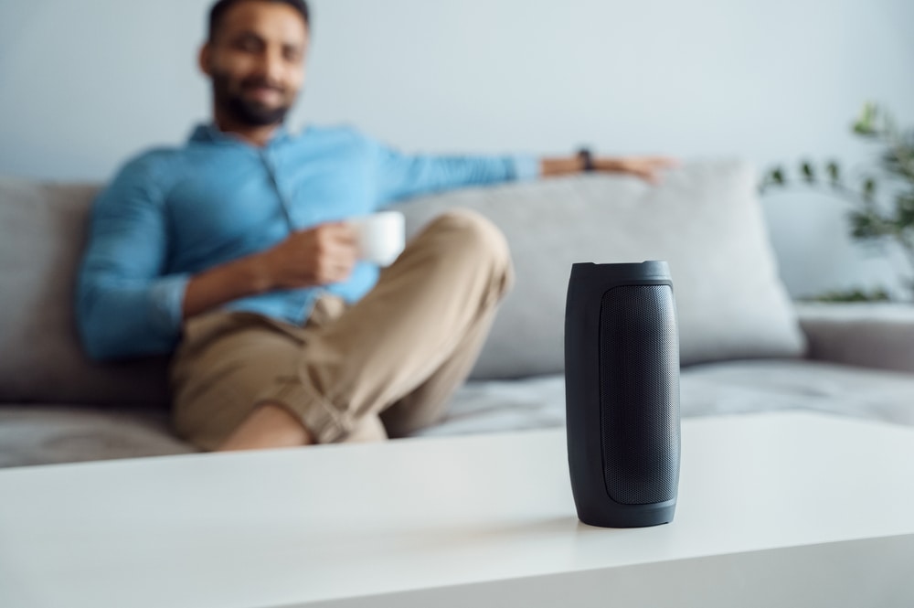 man on a sofa listening to a portable bluetooth speaker