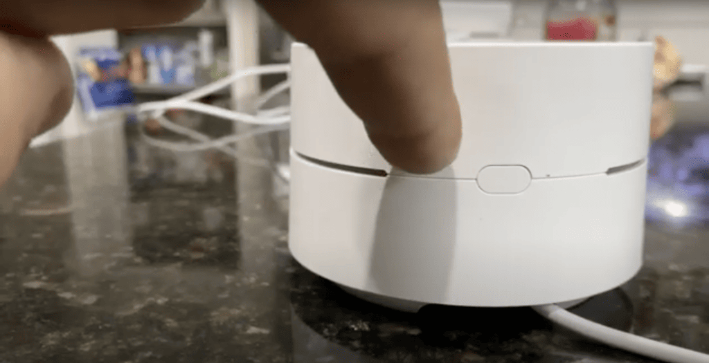 Pressing the button to factory reset a Google Wi-Fi
