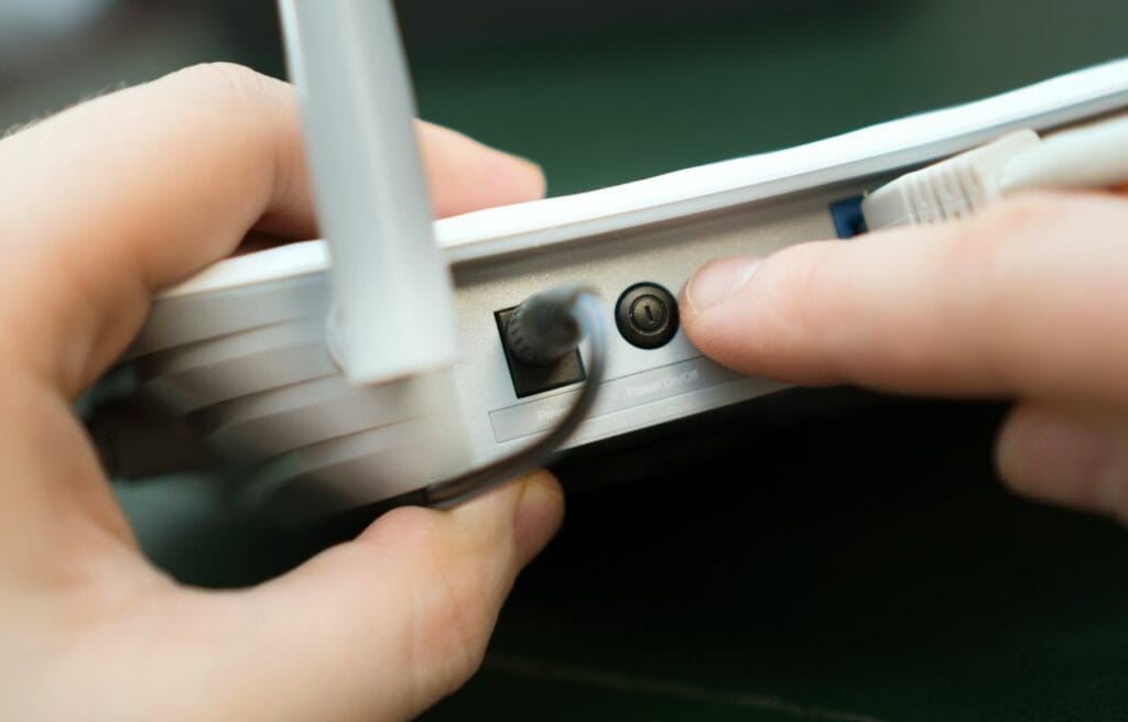 hand pressing the power button on a W-Fi router
