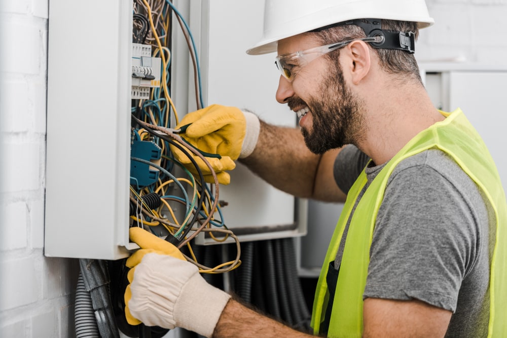 Male electrician fixing the wires with a smile